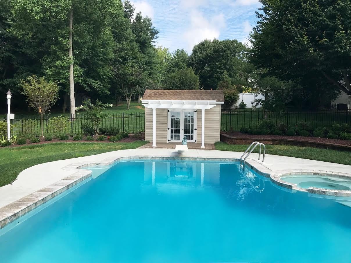 L-shaped inground gunite pool with attached spa, white pergola and matching pool house built by JHL Pools near West Chester, PA.